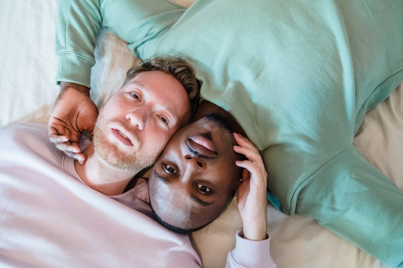 Close-up of an interracial couple lying down, embracing and looking content.